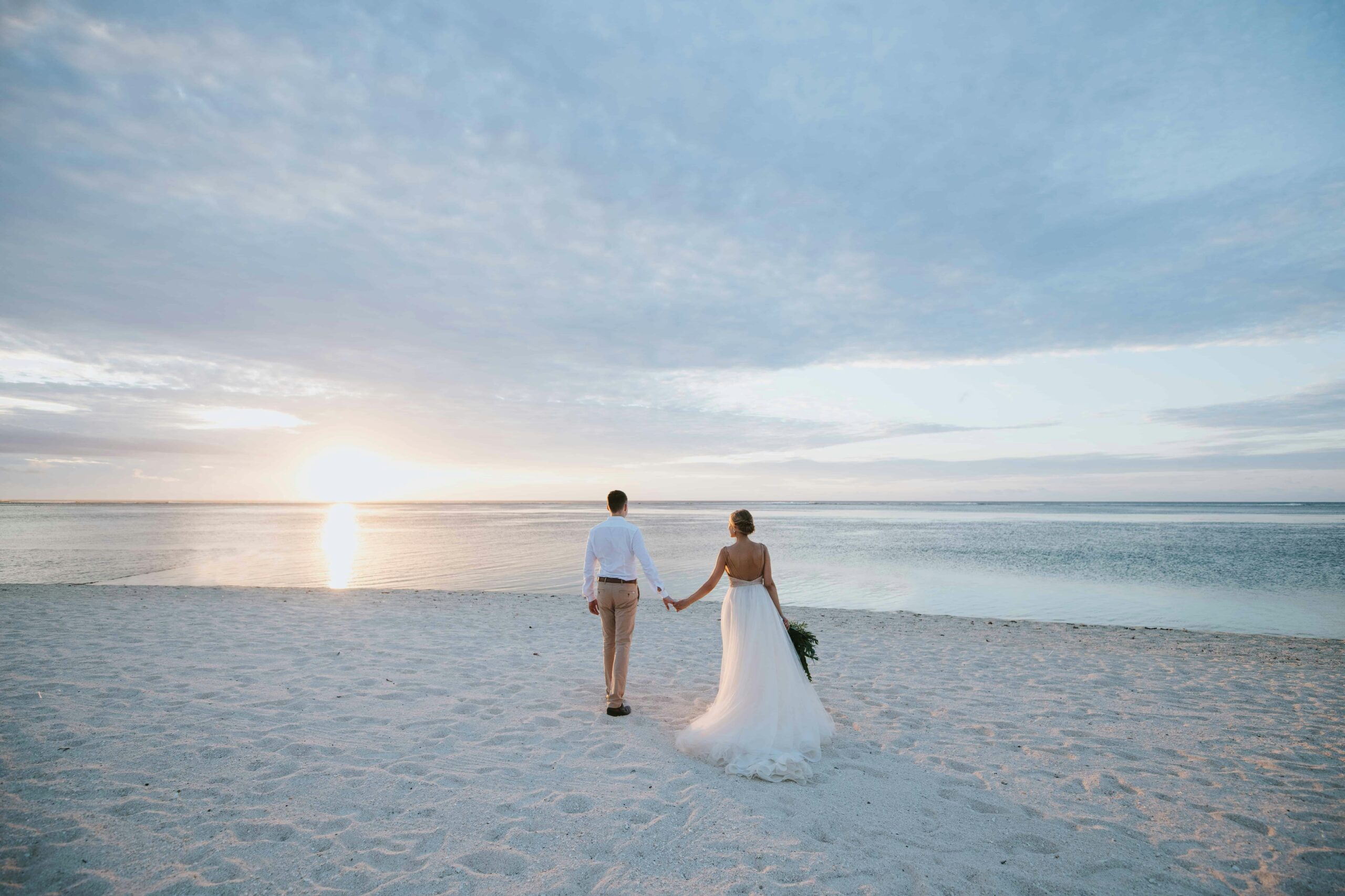 Couple holding hands on beach at sunset - LuxRide special events luxury transportation Florida