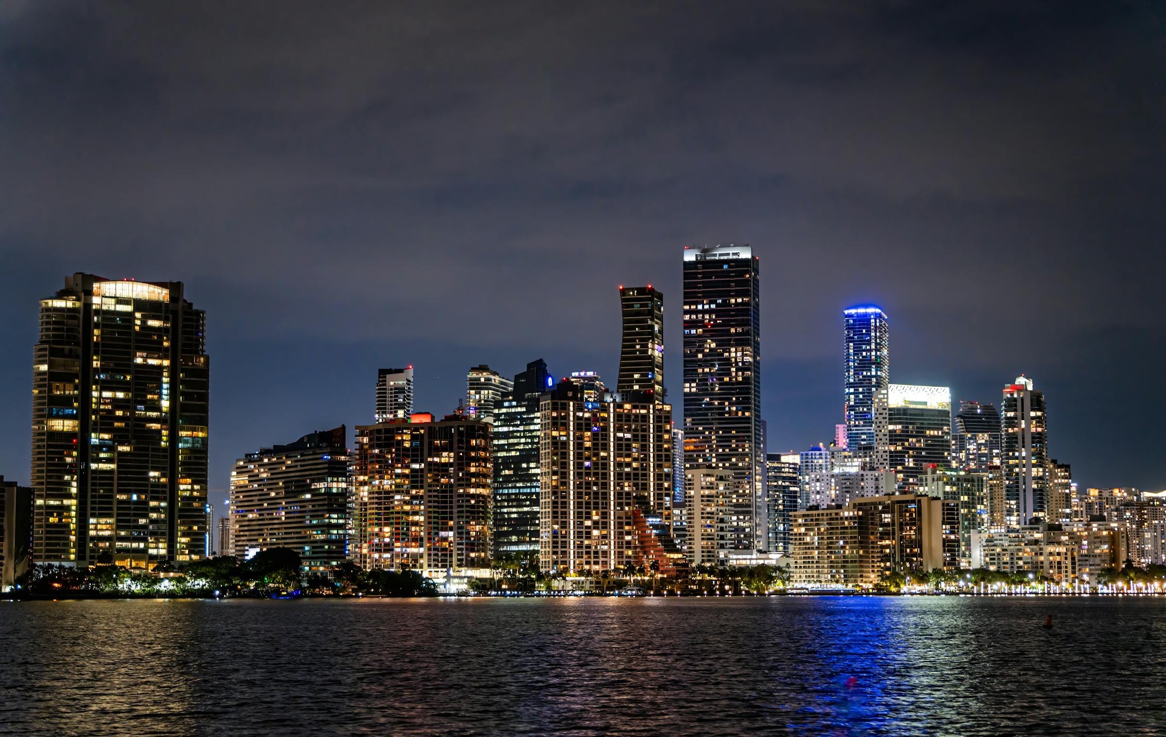 Miami skyline illuminated at night over Biscayne Bay - LuxRide interstate and long-distance chauffeur service