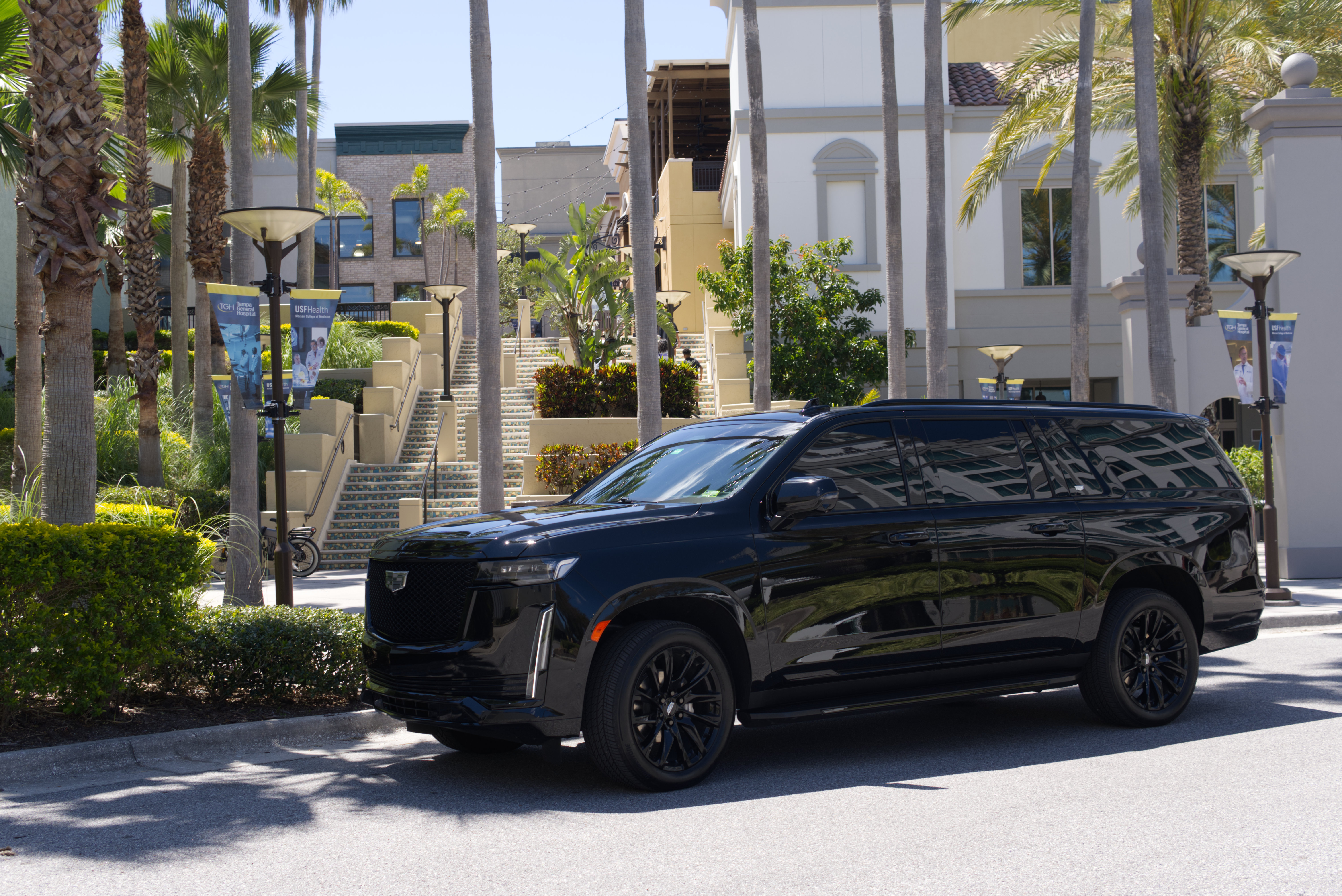 Black Cadillac Escalade at plaza with palm trees - LuxRide chauffeur service Tampa