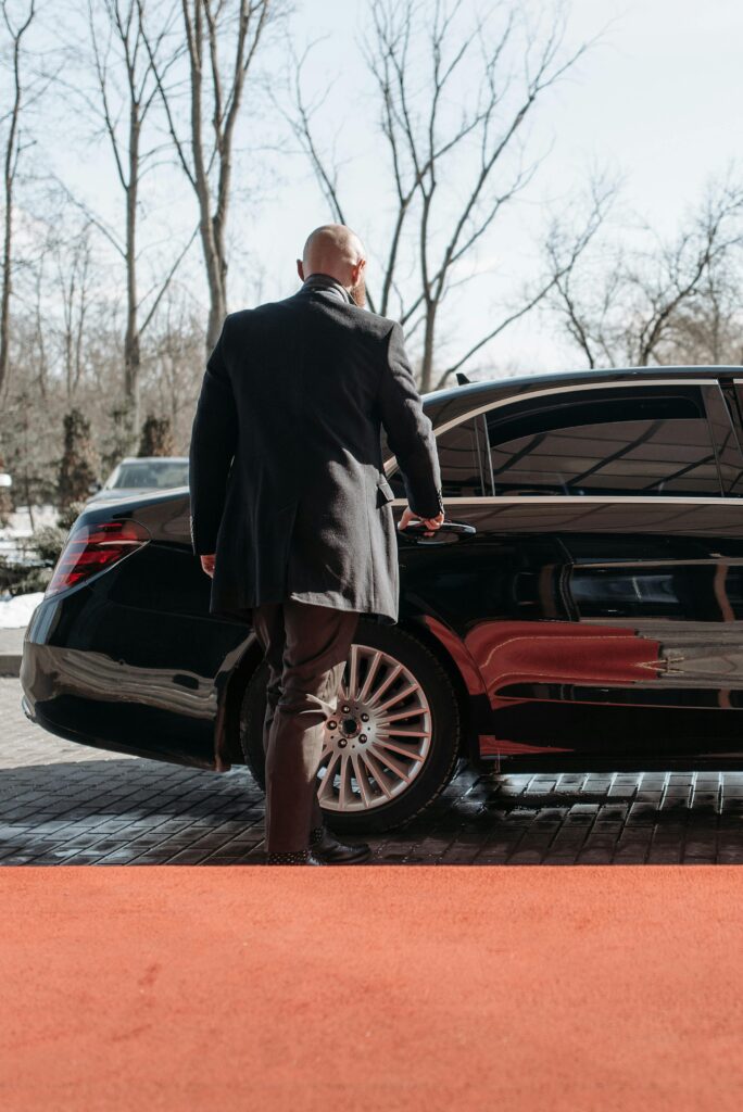 Seaport Transfer a private chauffeur standing next to a luxury car mercedes benz sedan opening the door